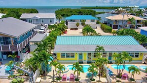 Ein Resort mit mehreren Gebäuden, einem zentralen Poolbereich und Blick aufs Meer.
