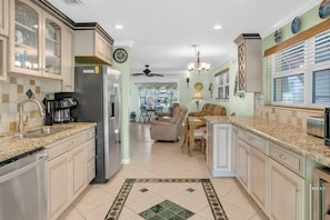 A spacious kitchen with granite countertops, a refrigerator, and a dining area with a chair and table. - P10 - Charming 2 bedroom, 2 bath duplex with private pool and deep water dockage. (Marathon)