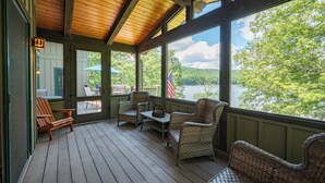 A wooden deck with wicker furniture and a view of a lake. - Elegant Lakefront Retreat w/ Hot Tub & Fireplaces (Oakland)