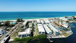 An aerial view of a coastal area with a marina, buildings, and a beach.