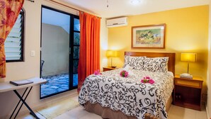 Una camera d'albergo con un letto, due comodini, una scrivania, una sedia, un climatizzatore e una finestra con tende.