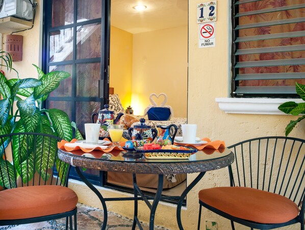 A breakfast setup on a small table with a view of a room and a window with blinds.
