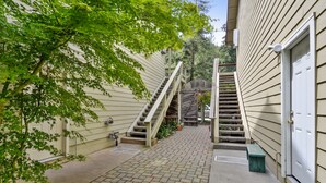 Un étroit sentier en briques menant à un escalier en bois et à une porte de garage.