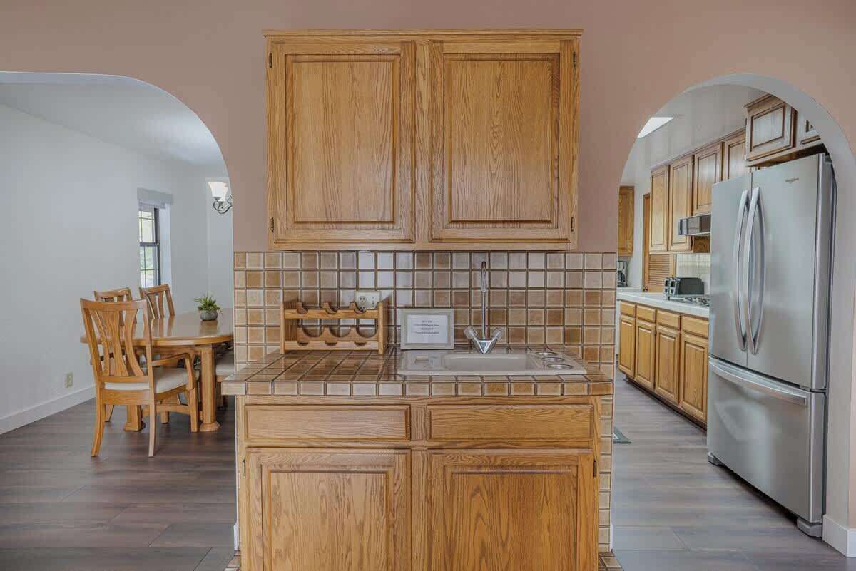 Una cocina con armarios de madera, salpicadero de azulejos y un refrigerador de acero inoxidable.