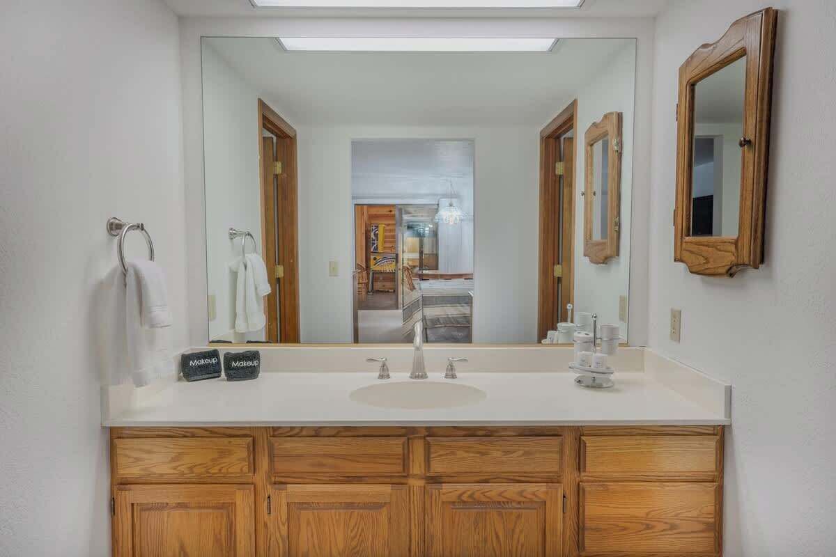 A bathroom with a double sink, wooden vanity, and a large mirror.