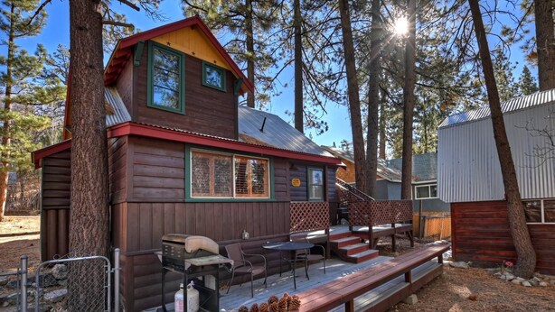 Eine rustikale Holzhütte mit einer Terrasse, Sitzgelegenheiten im Freien und einem Grill.