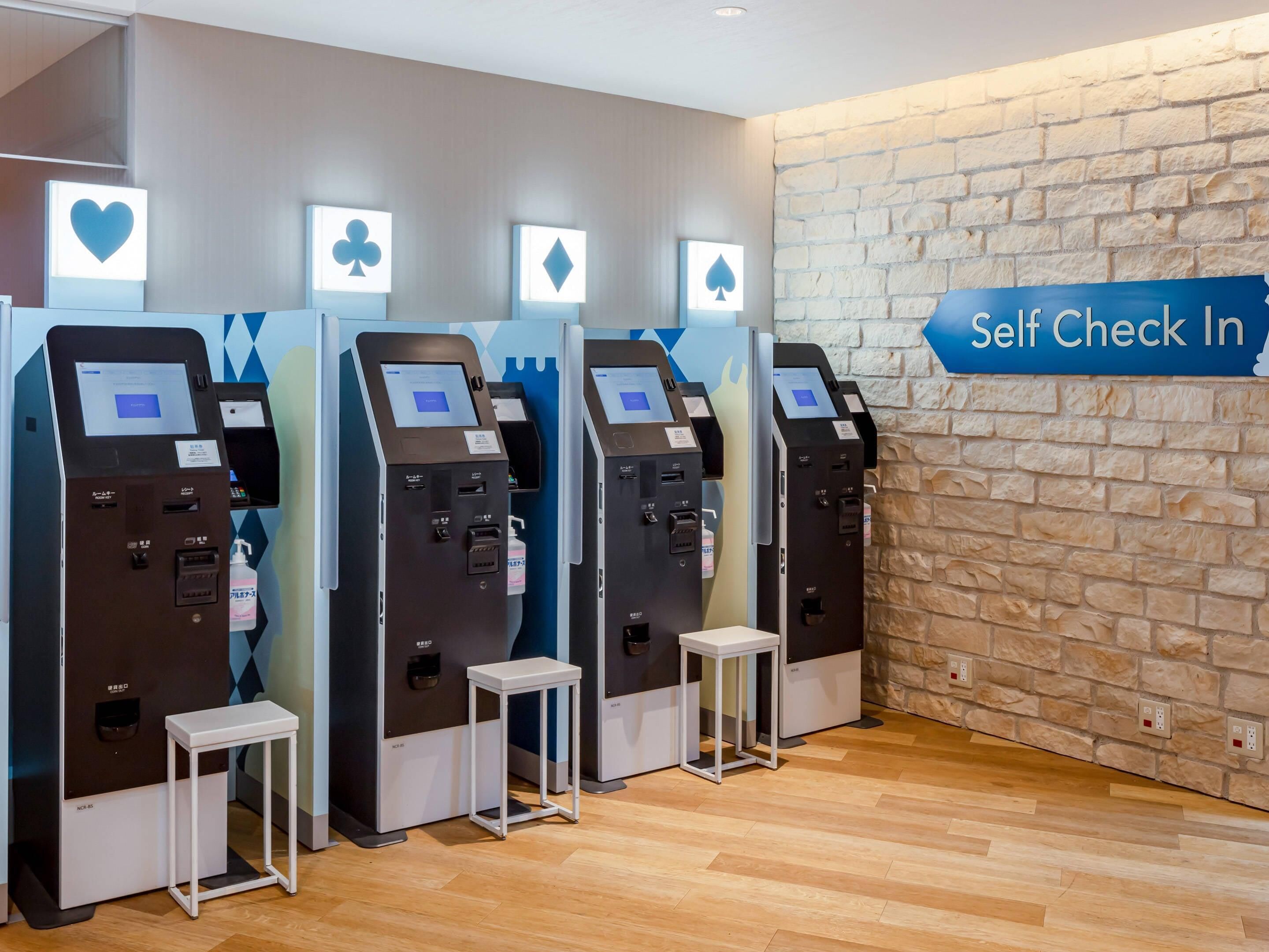 Self-check-in kiosks, a 'Self Check In' sign, and a stone wall.