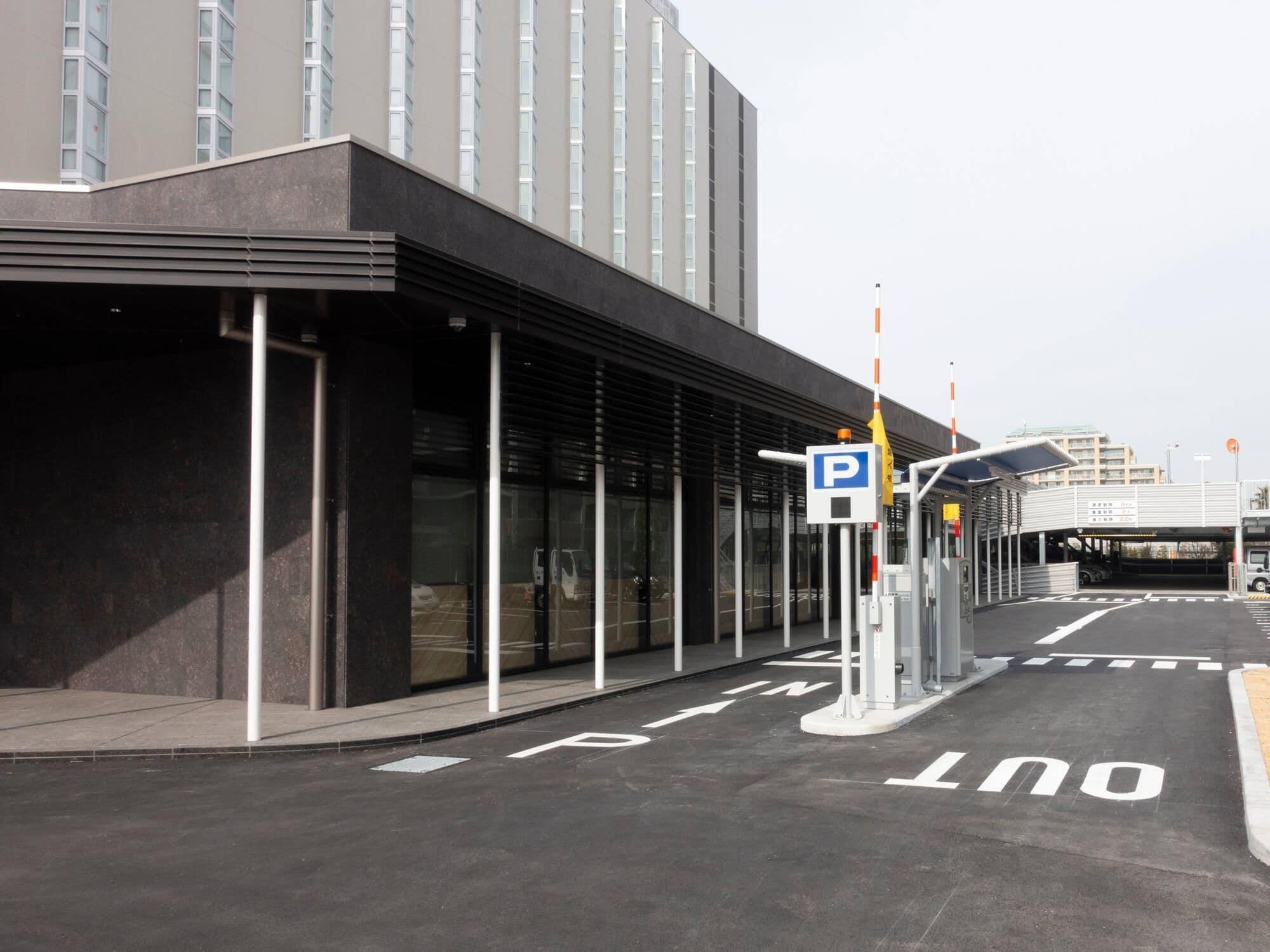 Een modern gebouw met een parkeeropgang, een overdekte doorgang en een helder zicht op de ingang.