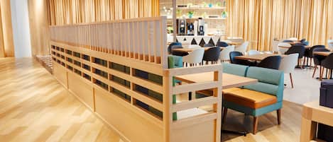 Un restaurante moderno con suelo de madera, asientos escalonados y una zona de bar.