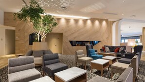 A modern lounge area with multiple seating options, a large tree, and a fireplace. - Comfort Suites Tokyo Bay (Urayasu)