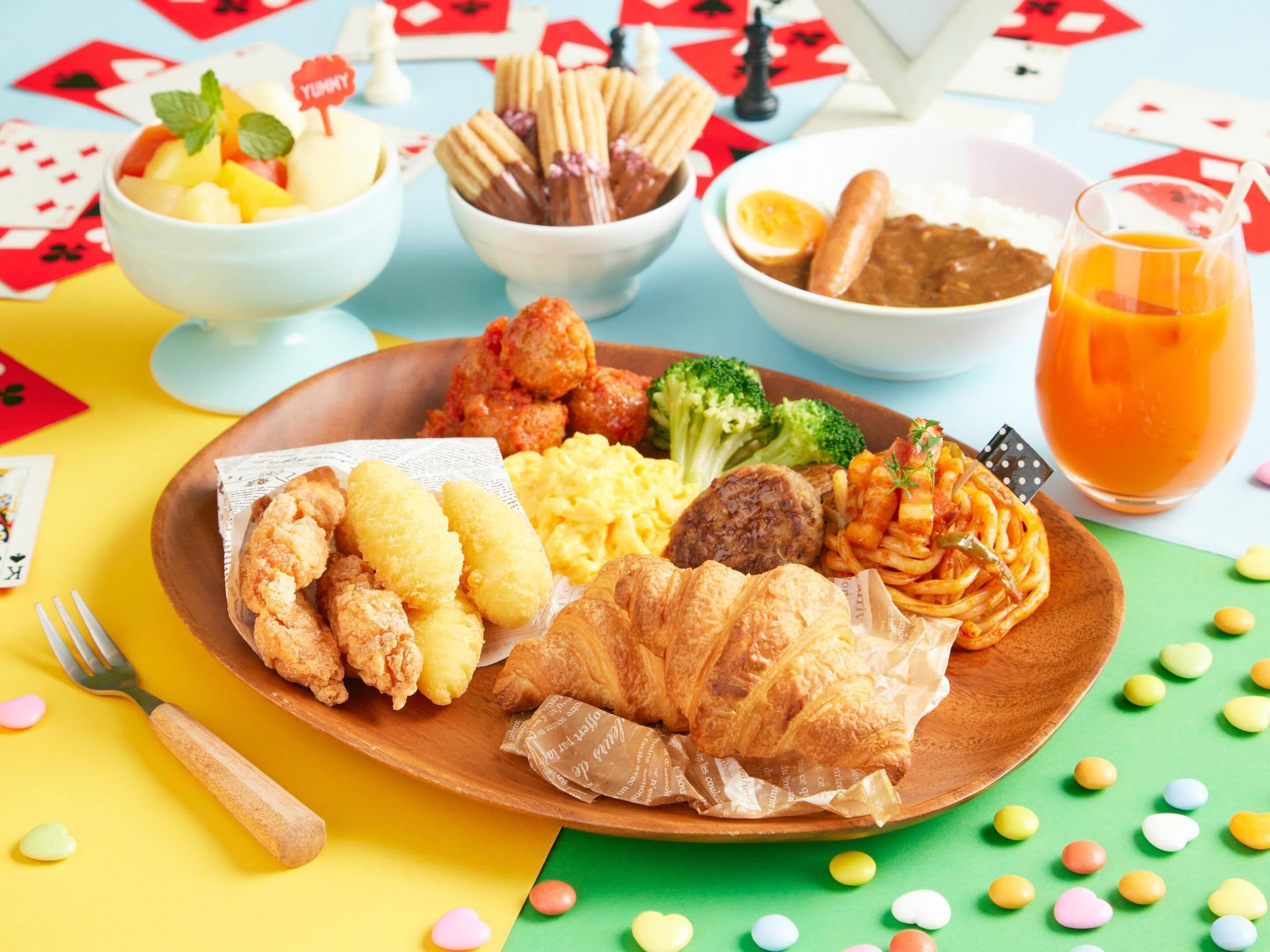 A meal with various dishes on a wooden plate, including fried items, vegetables, and a glass of orange juice.