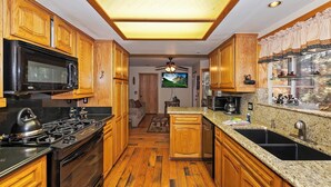A kitchen with wooden cabinets, a microwave, stove, and granite countertops. - HOT TUB! PET FRIENDLY! Two Game Rooms! Propane BBQ! Log Furnishings! WiFi! (Big Bear City)
