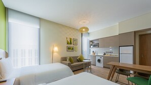 Une chambre d’hôtel avec deux lits, une kitchenette, un lave-linge et un coin repas.
