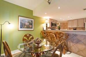Enjoy meals in this dining area with a round table and six chairs, surrounded by a framed picture.
