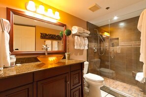 A bathroom with a large mirror, a vessel sink, a toilet, and a glass-enclosed shower.