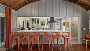 Une cuisine dotée d’un grand îlot central, de tabourets de bar et d’un plafond en bois.