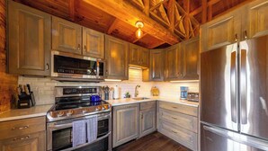 A modern kitchen with stainless steel appliances, wooden cabinets, and a wooden ceiling. - Log Cabin on Slate River | 4 Bedroom | Mt CB View | River Access (Crested Butte)