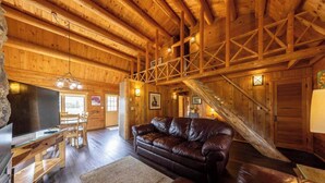 A wooden interior with a leather couch, wooden flooring, and a staircase. - Log Cabin on Slate River | 4 Bedroom | Mt CB View | River Access (Crested Butte)