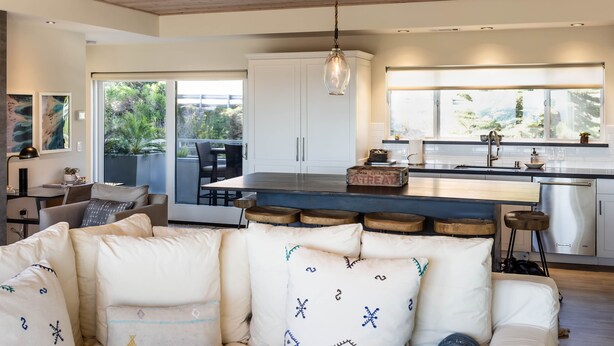 A modern kitchen with a large island, white cabinetry, and a view of greenery outside. - Luxury 2 Bed/2 Bath Penthouse in Shell Beach, Overlooking the Coast with Wrap-Around Balconies (Shell Beach)