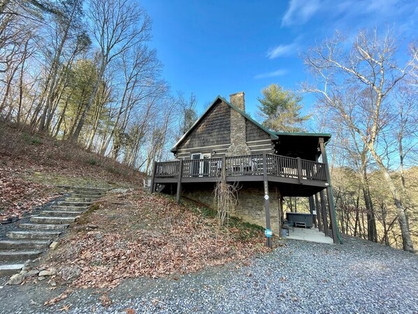 A cabin with a wooden exterior, a balcony, and a stone staircase leading up to it.