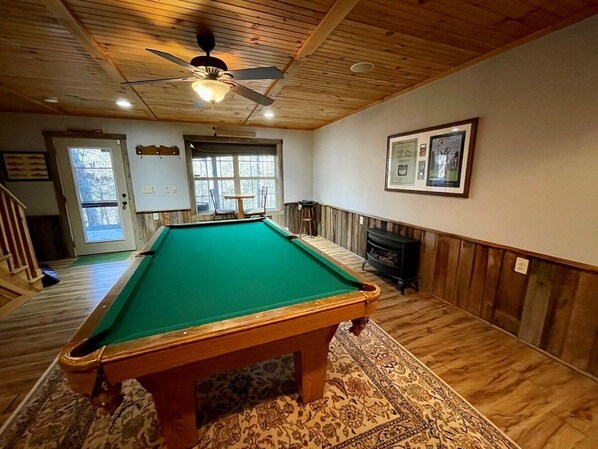 A pool table in a room with wooden floors and walls, a ceiling fan, and framed pictures on the wall. - High On Helton - Hot Tub, Fisherman's Paradise on Helton Creek, Pool Table, WIFI, Fireplace (Grassy Creek)