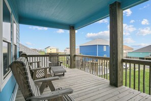 Um deck de madeira com guarda-corpo, um banco e vista para casas vizinhas.