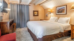 Une chambre à coucher avec un grand lit, un bureau avec une lampe, une chaise et un tableau au mur.