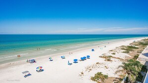 Ein Strand mit klarem, blauem Wasser, weißem Sand und einigen Sonnenschirmen.