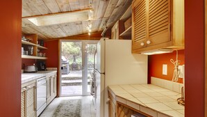 Une cuisine avec des meubles en bois, un réfrigérateur et un revêtement mural en carreaux.