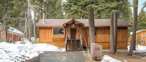 A cabin with a wooden exterior, a front door, and a small porch area.
