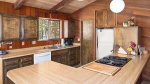Une cuisine avec des meubles de rangement en bois, un îlot central, un réfrigérateur et une cuisinière.