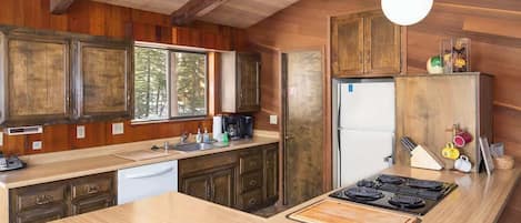 Une cuisine avec des meubles de rangement en bois, un îlot central, un réfrigérateur et une cuisinière.