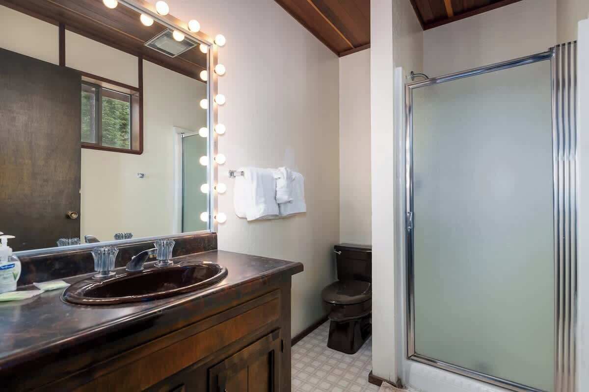 Un baño con tocador, espejo, iluminación y ducha.