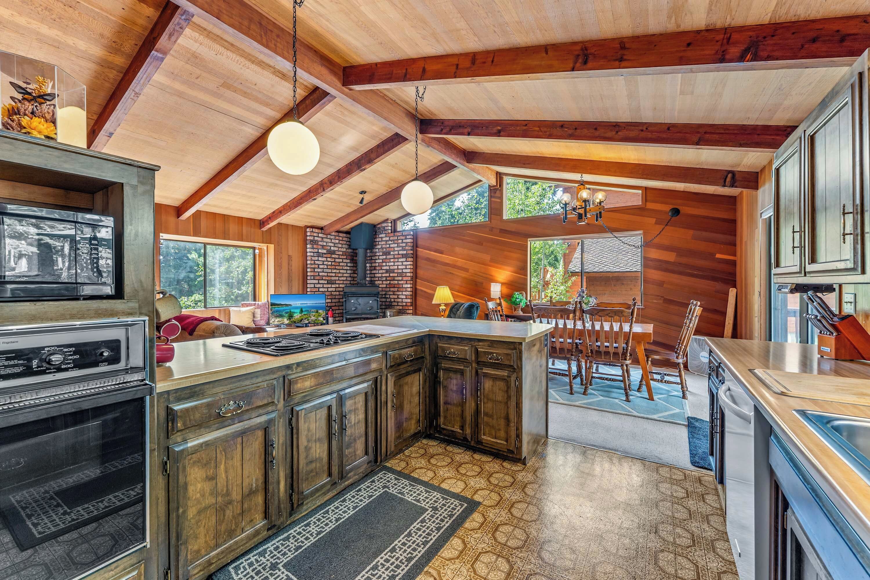 A kitchen with a central island, wooden cabinets, a built-in oven, and a hanging light fixture.