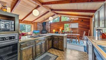A kitchen with a central island, wooden cabinets, a built-in oven, and a hanging light fixture.