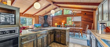Una cocina con una isla central, armarios de madera, horno empotrado y una lámpara colgante.
