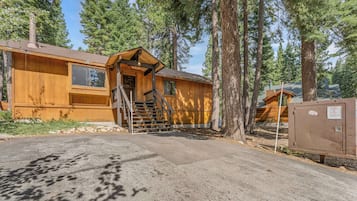 A wooden cabin with a front porch, a staircase, and a mailbox.