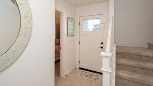 Un couloir avec une porte blanche, un petit tapis et un escalier recouvert d’une moquette beige.