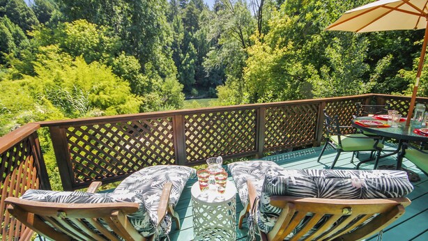 Eine Terrasse mit Gartenmöbeln, darunter Stühle und ein Tisch, umgeben von einem Holzzapfenzaun.