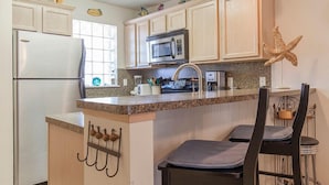 Una cocina con una isla central, un refrigerador, un microondas y un lavamanos.