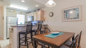 Una cocina con comedor, que incluye una mesa de madera, sillas, un refrigerador y un microondas.