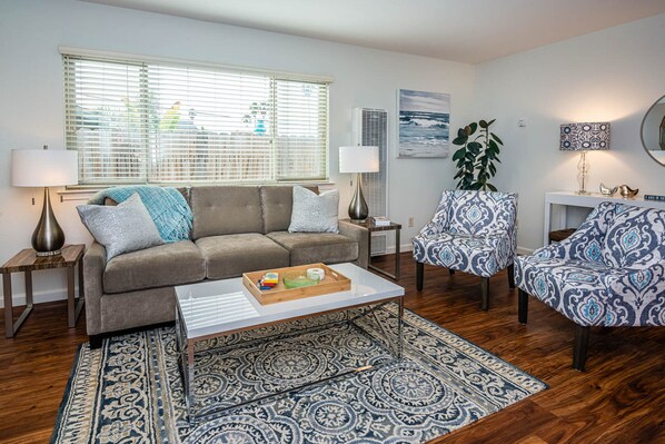 A living room with a sofa, two patterned chairs, a coffee table, and a rug.
