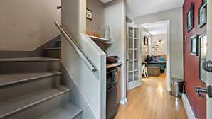 A staircase leading to a living area with a red wall and framed pictures. - Monte Rio Treehouse ~ Dog Friendly, Redwoods, Walk to Restaurants and River (Monte Rio)