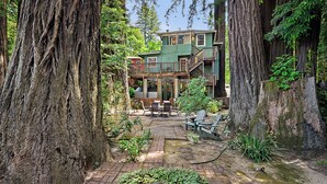 A two-story wooden house surrounded by tall trees. - Monte Rio Treehouse ~ Dog Friendly, Redwoods, Walk to Restaurants and River (Monte Rio)