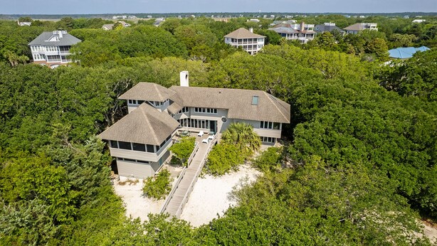 A large, multi-story house surrounded by dense greenery, with a prominent deck area and a visible garage. - Classic Second Row Beach House, Short Walk to the Beach (Georgetown)