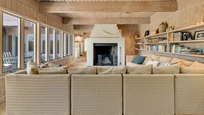 A cozy living room with a large sectional sofa, a fireplace, and a bookshelf filled with books. - Classic Second Row Beach House, Short Walk to the Beach (Georgetown)