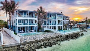 A beachfront property with a pool, multiple balconies, and a view of the ocean. - Felicity: Luxury Bayfront Home, Heated Pool, Hot tub and more! (Anna Maria)