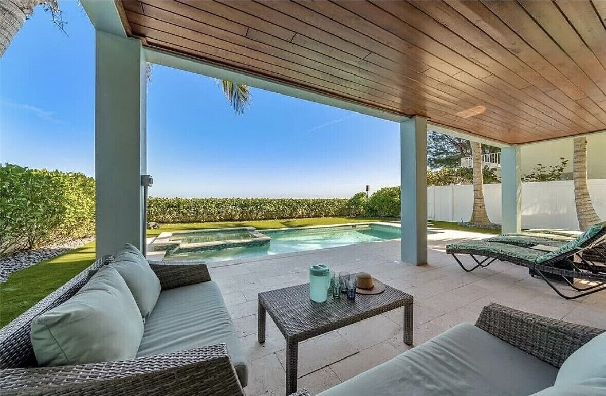 Une terrasse extérieure aménagée avec des meubles en osier, une piscine et une vue dégagée sur le paysage environnant.
