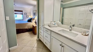 Une salle de bain avec un grand miroir, un lavabo et un dressing.