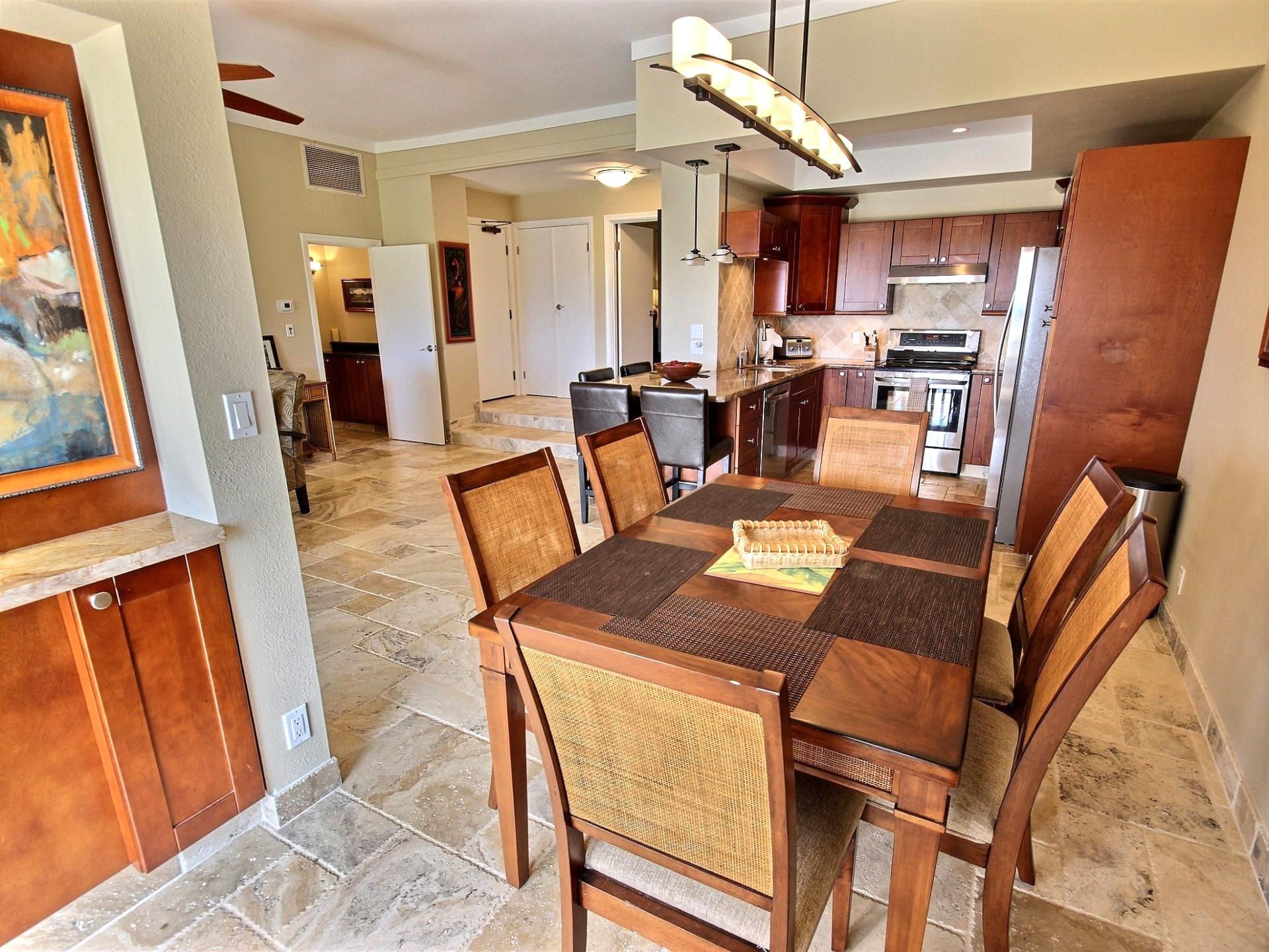 Un comedor amplio con una gran mesa de madera y sillas, una cocina al fondo y un pasillo que conduce a otra habitación.